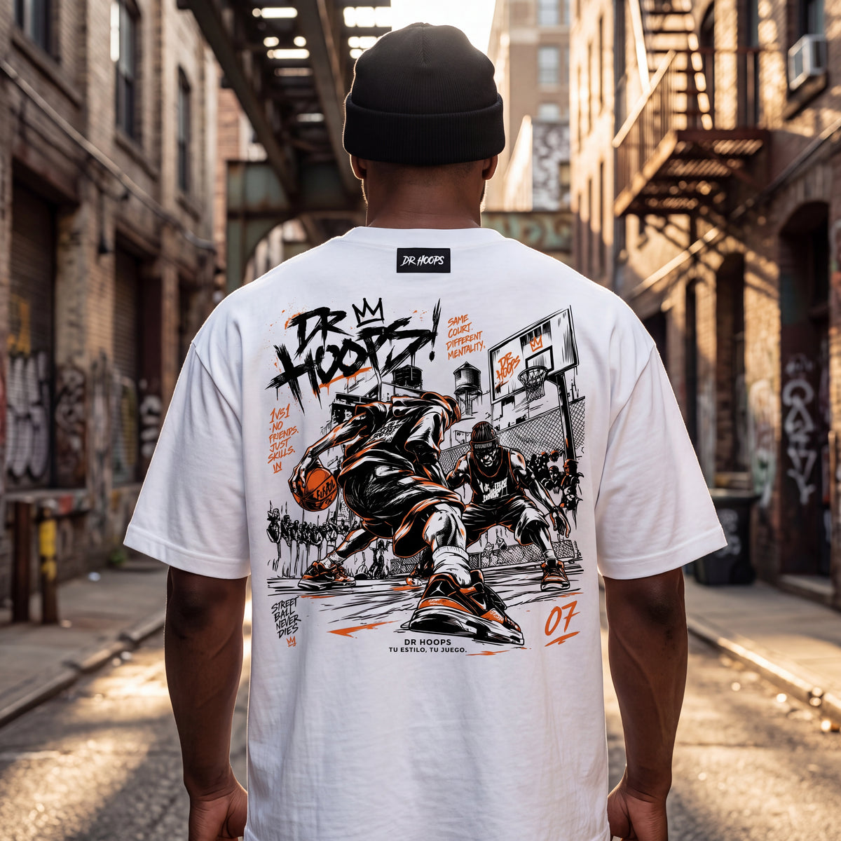 A man viewed from behind wearing a white t-shirt with a large black and orange basketball graphic on the back, standing in an urban alleyway.